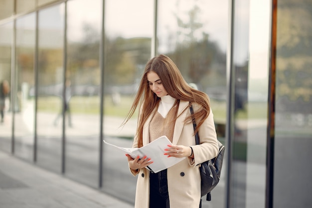 Girl standing in a spring city and hold documents in her hand