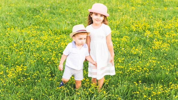 Girl standing with her brother in meadow