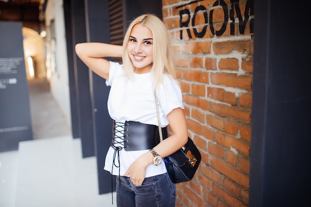 Free photo a girl stands at a wall of red bricks outdoors