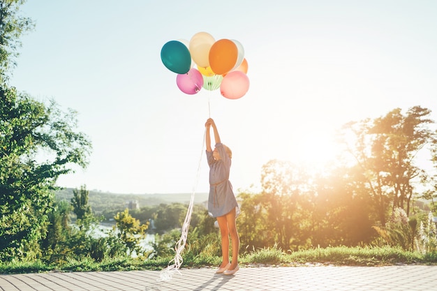 Free photo girl stretching to colorful balloons