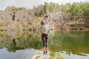 Free photo girl stretching her body on a lake rock