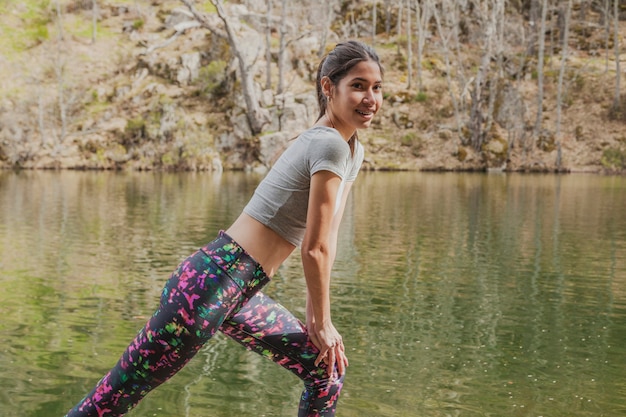 Girl stretching her legs with lake background