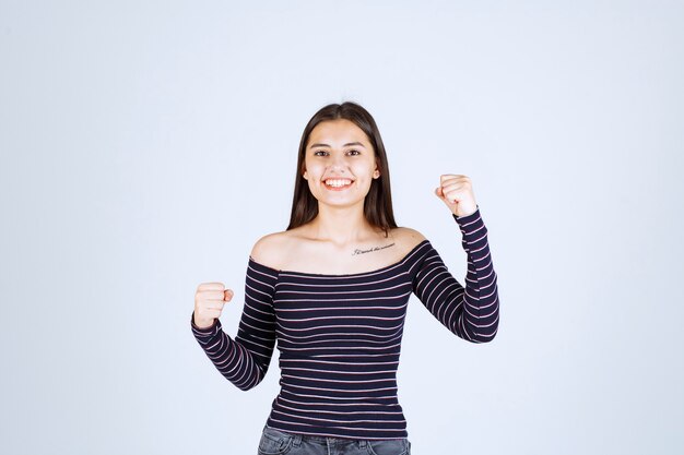 Girl in striped shirt demonstrating her arm muscles. 