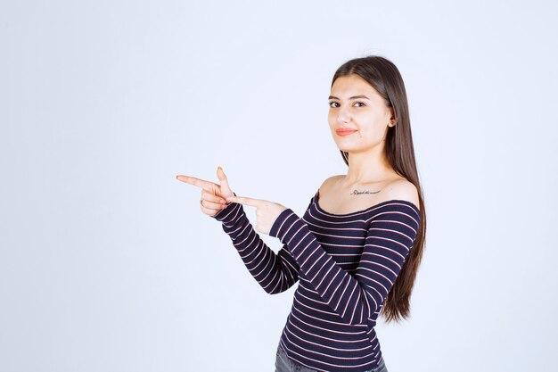 Girl in striped shirt pointing to the side. 