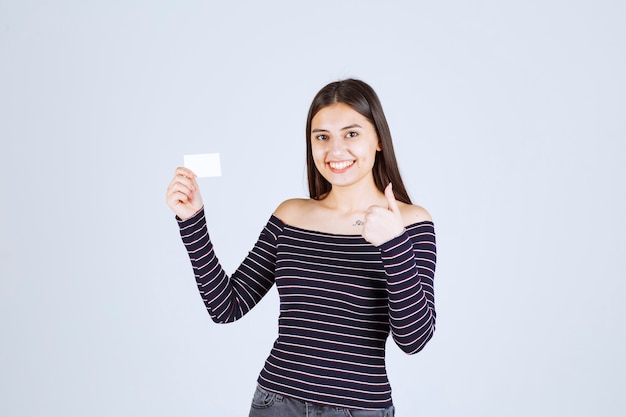 Girl in striped shirt presenting her business card with a confidence. 