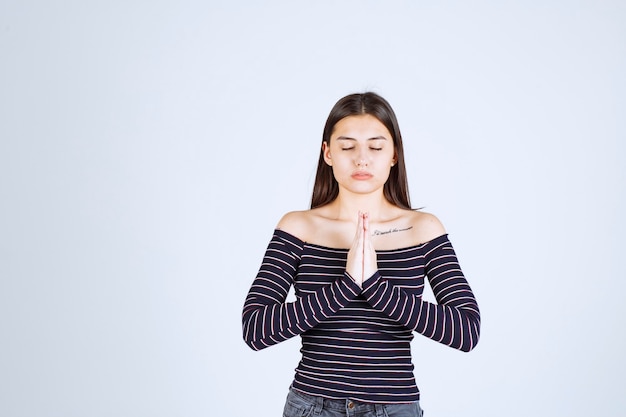 Free photo girl in striped shirt uniting her hands and praying.