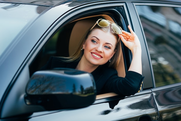 Girl in sunglasses drive a car and look from window