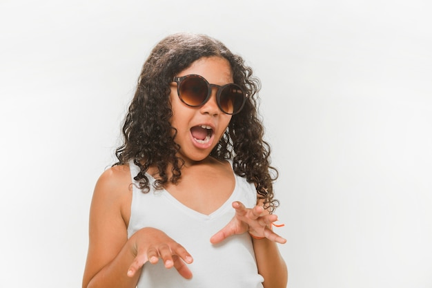 Girl in sunglasses trying to scare on white background