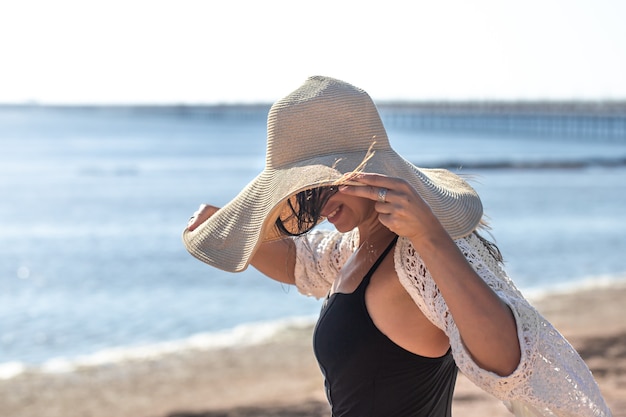 Free Photo the girl in a swimsuit covered her face with a large hat. summer vacation concept at sea.