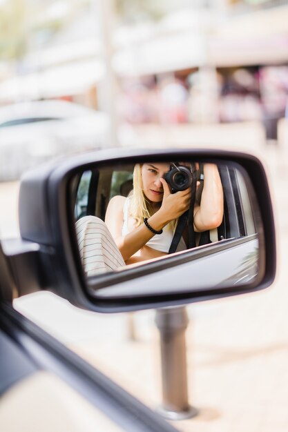 a girl takes a picture of herself in a car mirror