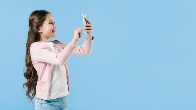 Girl taking picture with phone in studio