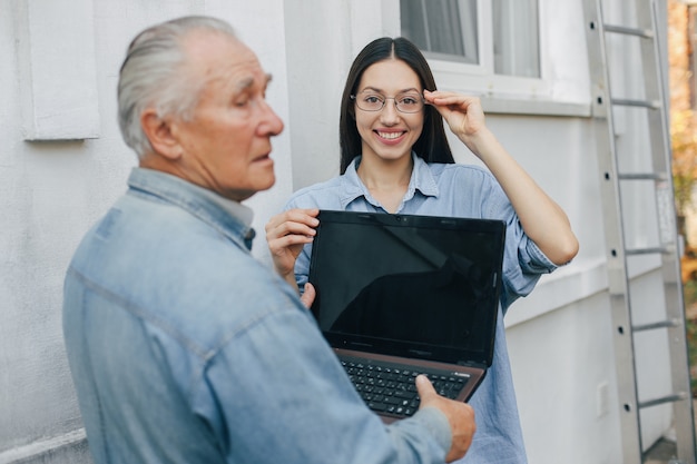 Girl teaching her grandfather how to use a laptop