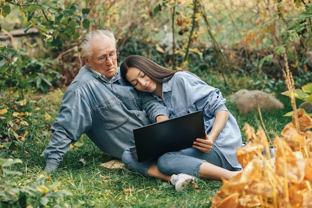 Girl teaching her grandfather how to use a laptop