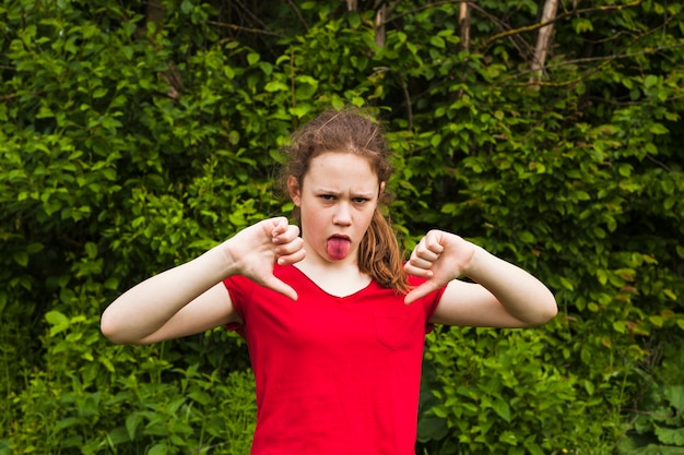 Girl teasing with sticking out tongue looking at camera in park