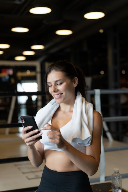 Girl texting while taking a break in a gym. Reads a message