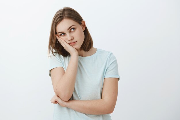 Girl thinks party lame. Bored young european female with short brown haircut leaning head on palm gazing at upper right corner thinking using imagination to entertain herself while dying from boredom