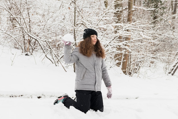 Free Photo girl throwing snowball in winter forest