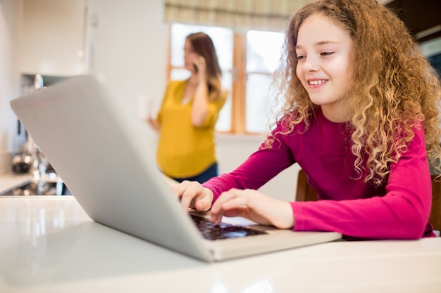 Girl using laptop in kitchen