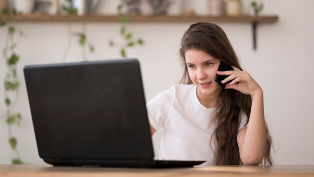 Girl using laptop and talking over phone