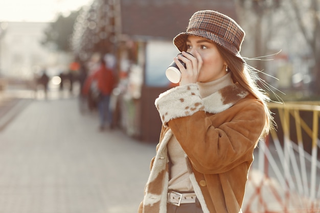 Girl walking in a spring city and taking a coffee