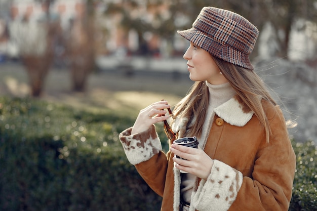 Girl walking in a spring city and taking coffee