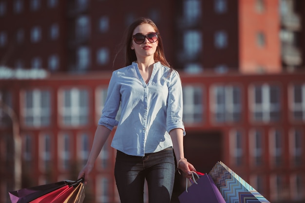 Free photo the girl walking with shopping bags on city streets at sunny day