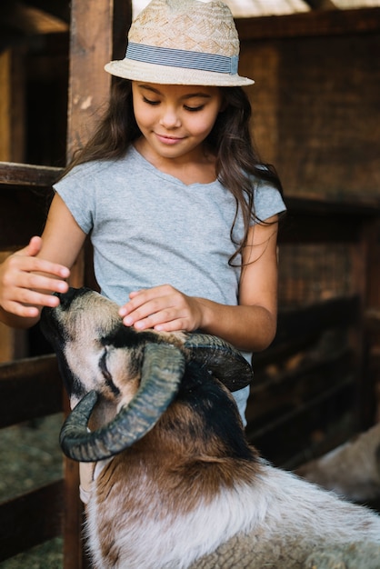 Girl wearing hat patting sheep