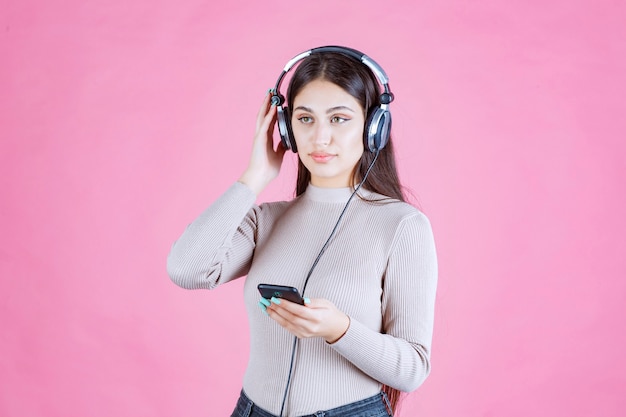 Free Photo girl wearing headphones and setting music at her smartphone