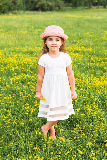 Girl in white dress standing in the meadow holding yellow flowers