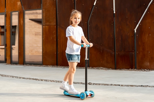 Girl in white t-shirt riding blue scooter