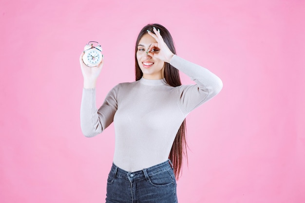 Girl with an alarm clock making enjoyment sign