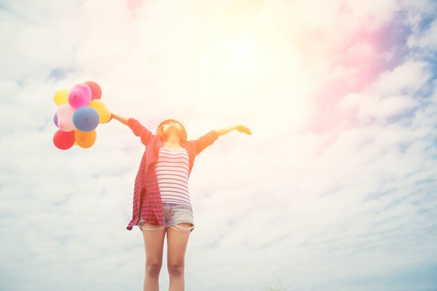 Girl with arms streched and colored balloons