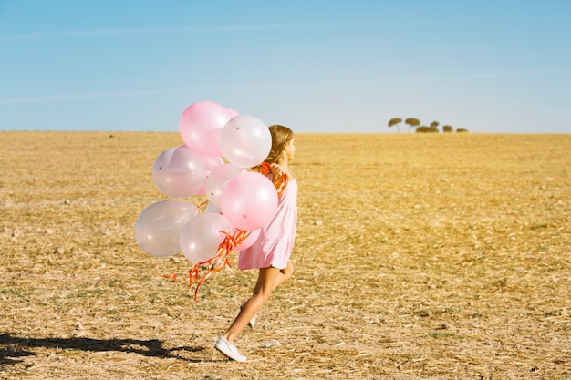 Free Photo girl with balloons running in field