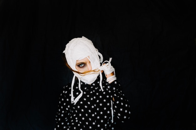 Girl with bandaged face on black background