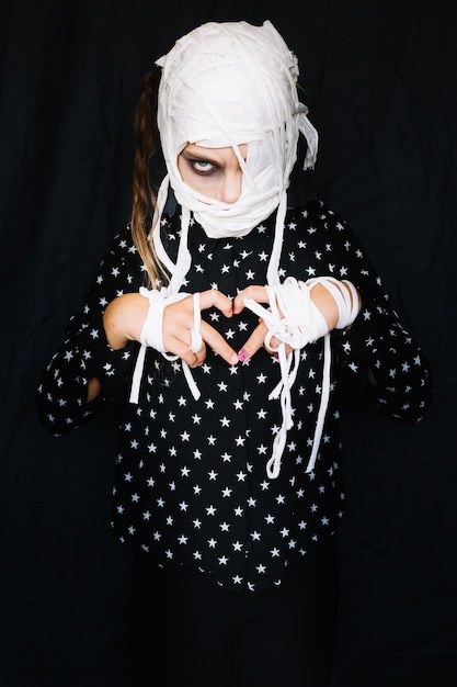 Free Photo girl with bandaged face making heart sign