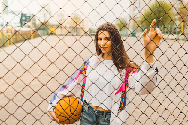 Free photo girl with basketball behind fence