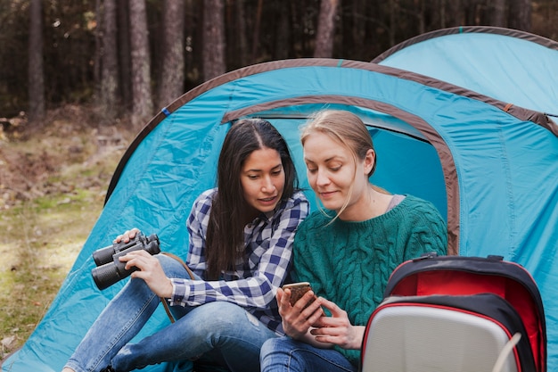 Free photo girl with binoculars and looking at her friend's cell phone