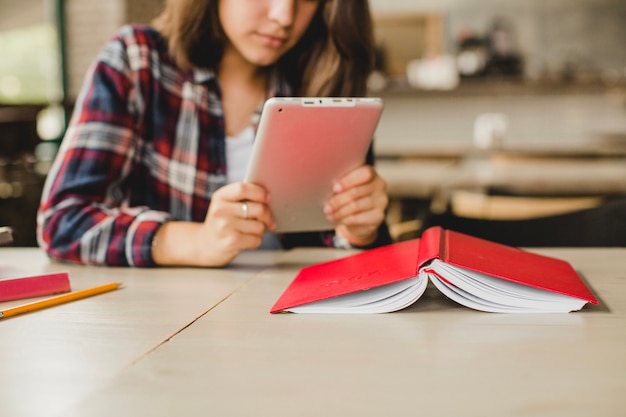 Girl with book and tablet at table