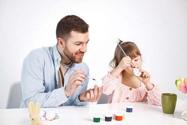 Girl with Down syndrome and her father painting Easter colored eggs