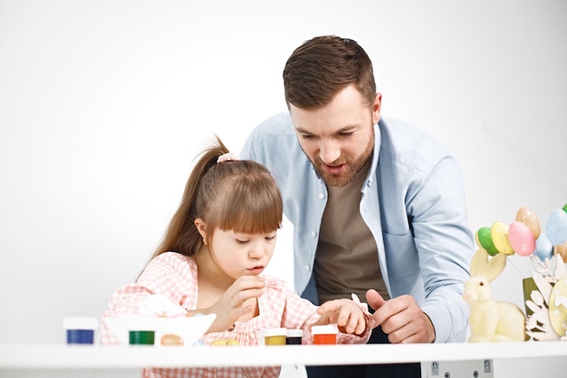 Free photo girl with down syndrome and her father playing with easter colored eggs