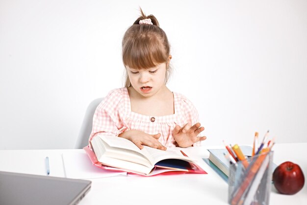 Girl with Down syndrome studying while sitting at desk at home