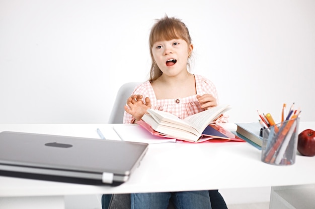 Girl with Down syndrome studying while sitting at desk at home