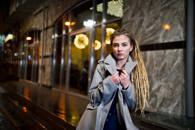 Girl with dreadlocks walking at night street of city