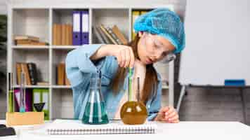 Free photo girl with hair net doing science experiments with test tubes