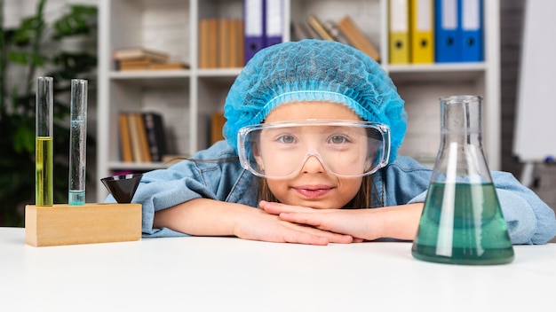 Free photo girl with hair net and safety glasses doing science experiments with test tube