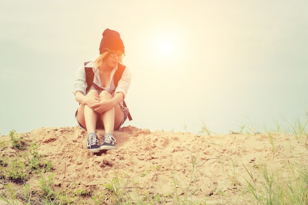 Girl with hat sitting on sand