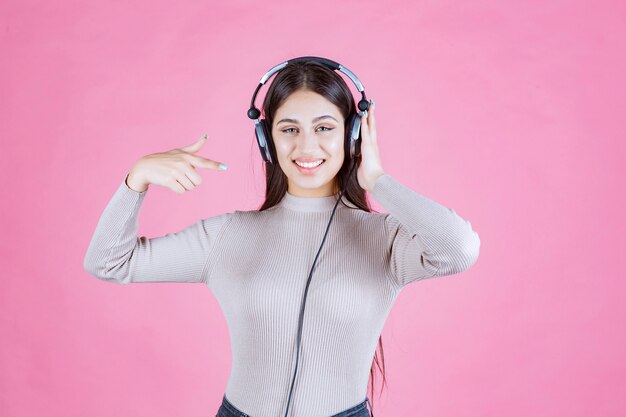 Girl with headphones pointing at her device