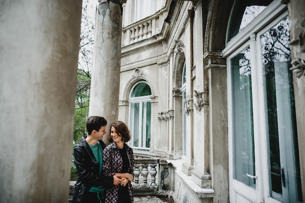 Girl with her boyfriend stand near old building and smile to each other