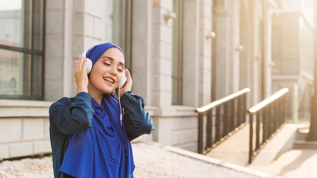 Free photo girl with hijab listening to music through headphones