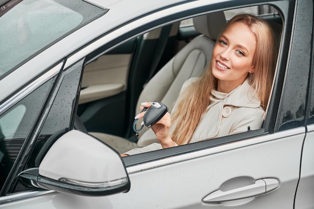 Girl with keys in hands sitting in driver's seat of car